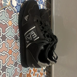 Armani sneakers - Ett par svarta Armani skor i storlek 41. Mycket bra skick 9/10 och knappt någon crease på skorna. Väldigt sköna och ganska lätta skor. Nypris cirka 1500 säljer för 750 kronor pga att de är för små för mig. Använda cirka 9 gånger och köpte dem på JD. 