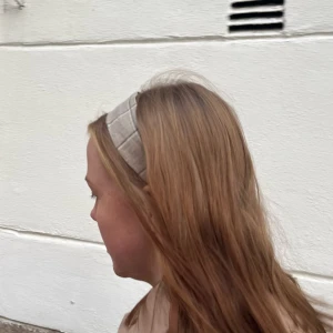 Beiget/Grått hårband med knapp - Jättesnyggt hårband med knapp en bit bakom örat. Knappen hindrar att smink kladdar på hårbandet och ger en snygg look utan ansträngning💚