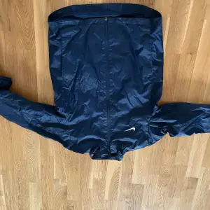 En mörk blå Nike regnjacka i bra skicka utan luva i storleken 147-158 cm