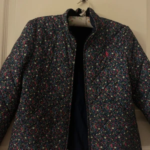 Blommig quiltad Ralph Lauren täckjacka - Säljer min superfina, coola och unika jacka från Ralph Lauren som är köpt på NK för några år sedan. Den i väldigt gott skick men är i barnstorlek så passar inte mig längre, därav jag säljer den.💗 Den är i storlek L(12-14), kan möjligen passa en XXS.