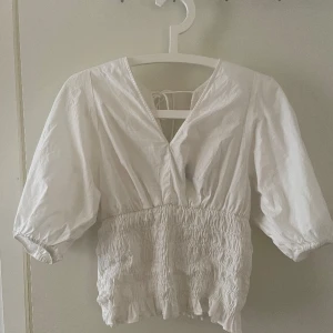 Vit blus - Säljer denna jättefina blusen i stl M då den bara kom till användning 1 gång. Går att knyta där bak och passar även någon som är stl S💕