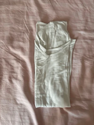 Vit basic t-shirt med v-ringning - En enkel vit t-shirt med v-ringad hals och korta ärmar. T-shirten har en loose passform och är tillverkad i mjuk bomull, perfekt för en avslappnad stil. Passar till det mesta och är ett måste i garderoben. Observera en mindre fläck som ej syns när man bär toppen. 