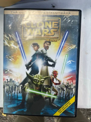 Star Wars: The Clone Wars DVD - Säljer en DVD med filmen Star Wars: The Clone Wars. Omslaget har färgstarka illustrationer av karaktärer som Yoda, Anakin och Obi-Wan med ljussablar. Tvådisc specialutgåva med både svensk och engelsk text och tal. Perfekt för Star Wars-fans och samlare.