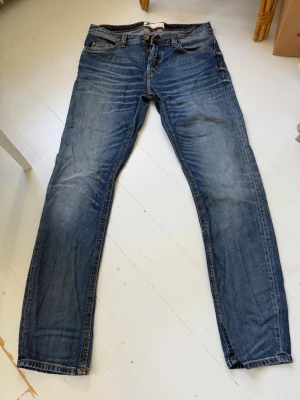 Blå raka jeans med klassisk tvätt - Snygga blå jeans med klassisk tvätt och raka ben. Jeansen har fem fickor, bälteshällor och knappgylf. Perfekta för en avslappnad och stilren look. Passar till det mesta och är ett måste i garderoben.