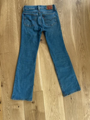 Blå bootcut jeans med vintagekänsla - Ett par blåa superlow boot jeans ifrån Levis, storlek w24. 