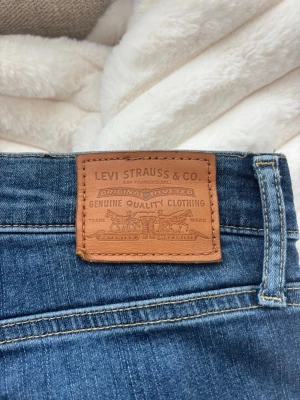 Blå Levi's jeans med klassisk passform - Säljer ett par blå jeans från Levi's med klassisk femficksmodell och ikonisk läderpatch bak i midjan. Jeansen är skinny modell och är tillverkade i slitstark denim. Använda 2 gånger.