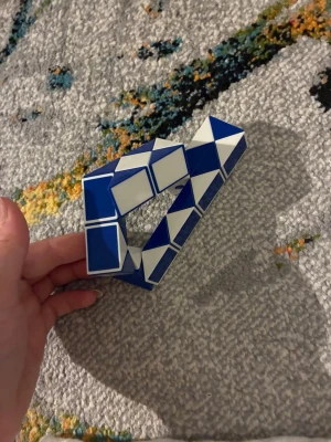 Blåvit magisk orm leksak - Säljer en blåvit magisk orm, även kallad twist-pussel. Den består av flera vridbara triangulära segment som kan formas till olika figurer. Perfekt för dig som gillar att pyssla eller vill ha något att fippla med under plugget.
