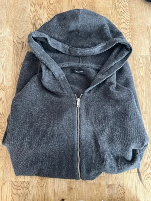 Mörkgrå zip hoodie - Säljer en mörkgrå hoodie från Jack & Jones med dragkedja framtill och stor huva. Perfekt för dig som gillar en enkel och stilren look. Passar till det mesta och är riktigt bekväm.