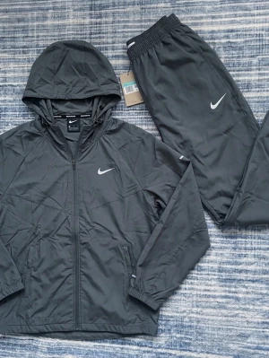 Nike grå träningsset - Lättviktig tracksuit.   Längd: 65cm Armhåla till armhåla:55cm Arm längd: 63cm  Byx längd: 97cm