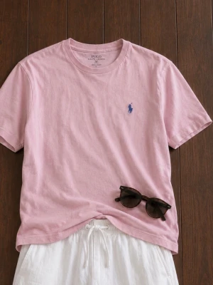 Rosa t-shirt från Polo Ralph Lauren - Snygg rosa t-shirt från Polo Ralph Lauren med klassisk passform och blå logga broderad på bröstet. Tillverkad i mjuk bomull och har rund halsringning samt korta ärmar. Perfekt till sommaren för en clean och avslappnad stil.