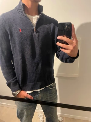 Polo Ralph Lauren quarterzip  - Marinblå stickad quarterzip från Polo Ralph Lauren. Tröjan har endast används ett par gånger och är i utmärkt skick. Skriv gärna vid frågor och funderingar!