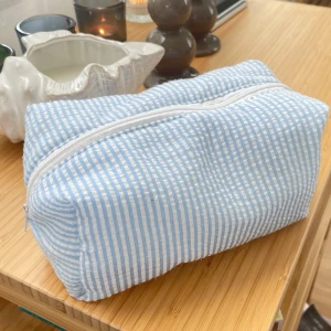 Blåvit randig necessär i tyg - Säljer en söt necessär i blåvitrandigt tyg med vit dragkedja. Väskan har en rektangulär form och är perfekt för att förvara smink, småprylar eller andra accessoarer. Enkel och stilren design som passar i väskan eller på resan. Skick enligt bild