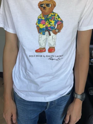Vit Polo Bear t-shirt från Ralph Lauren - Vit t-shirt från Ralph Lauren med Polo Bear-tryck framtill. Är i barn storlek men passar om man har storlek S