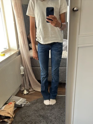 Blå bootcut jeans med låg midja - Säljer ett par klassiska blå bootcut jeans med låg midja och fem fickor. Jeansen har en snygg tvätt och kontrastsömmar. Passar perfekt till en avslappnad och trendig stil. Materialet är denim i bomull. Har aldrig använt dessa! Köpt på zalando, storlek 25/32