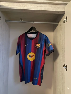 Barcelona Hemma 26/27 Fotbollströja - Helt ny och trendig Barcelona 2026 / 2027 säsongs Hemma version fotbollströja. Nypris runt 1099kr. Passformen på tröjan är som en oversized t-shirt i storlek S. Tröjan kommer med original förpackning och skickas i förstärkt påse för att hindra skador eller slit under frakt. Kontakta vid funderingar, och kolla min profil om du vill se andra tröjor. 