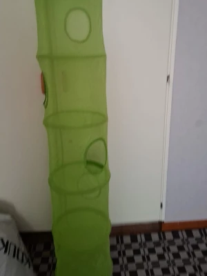 Grön hängande förvaringsficka - Praktisk grön hängande förvaringsficka i nätmaterial med flera runda öppningar. Perfekt för att organisera småsaker, leksaker eller accessoarer. Cylindrisk form och lätt att hänga upp i garderob eller på vägg.