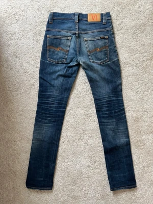 Blå jeans från Nudie Jeans - Ett par SJUKT feta jeans ifrån märket Nudie Jeans med riktigt snygga fades. Storleken är 29-32 och modellen är Thin Finn. Jeansen har en snygg passform utan defekter! Ifall du vill ha fler bilder så skriv!  😁✌🏼 ——————————————————————————                                      📐| Storlek: 29-32                                                  👖| Märke: Nudie jeans                                         🔎| Skick: Fint skick!                                              💵| Ny Pris: 1699kr
