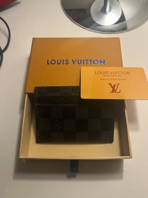  Svart kortfodral - Snyggt svart kortfodral i klassiskt rutmönster Damier Graphite. Tillverkat i tåligt läder med plats för flera kort. Perfekt accessoar för dig som vill ha stil och funktion i ett. Levereras med originalask och äkthetskort.