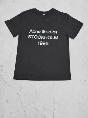 Svart Acne Studios t-shirt - Cool svart t-shirt från Acne Studios med vit text 'Acne Studios STOCKHOLM 1996' på bröstet. Klassisk passform med rund hals och korta ärmar. Perfekt till jeans eller shorts för en avslappnad look.