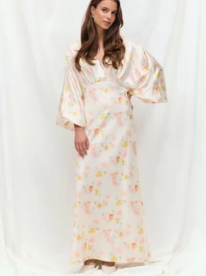 Lång blommig klänning med vida ärmar - Elegant långklänning i ljusa toner med blommigt mönster. Klänningen har v-ringning och vida, långa ärmar som ger en flowy känsla. Tillverkad i ett glansigt material som påminner om siden eller polyester. Perfekt för sommarens alla tillfällen. Prislappen kvar 699 kr 