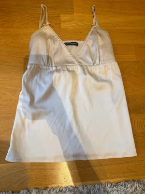 Satin linne - Supergulligt satin linne från Brandy Melville med rosetter och knytband i bak. Storlek Onesize men passar mig som vanligtvis har XS. Justerbara axelband! Använd en gång, så i princip ny. Hör av er vid frågor/prisförslag