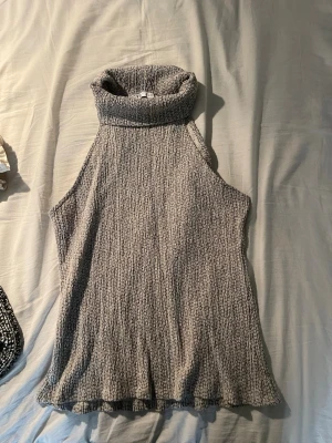 Grå polotopp från Zara - Säljer en grå polotopp från Zara med hög krage och ärmlös design. Toppen har en strukturerad, lite ribbad yta och är i ett mjukt, stretchigt material. Perfekt för att styla med jeans eller kjol för en trendig look.