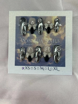 BadAngel (XS);Meidum Almond - Unika handgjorda press-on naglar i silver och svart med charms. Naglarna har en medium längd, mandelform och är handgjorda för en edgy och konstnärlig look. Perfekt för dig som vill sticka ut med en futuristisk och kreativ stil.XS: 14 mm, 11 mm, 11,5 mm, 10 mm, 8 mm