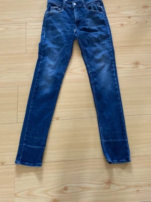 Mörkblå slim fit jeans - Snygga mörkblå slim fit jeans med klassisk femficksdesign och lätt slitna detaljer. Jeansen har normal midja och raka ben, perfekta för en avslappnad och trendig look. Materialet är denim i bomull med lite stretch för extra komfort.