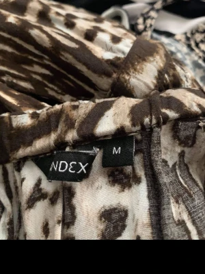 Mönstrade jumpsuit från INDEX - Säljer ett par jumpsuit från INDEX i storlek M med djurmönster i svart, brunt och vitt. De har en smal passform och är tillverkade i ett mjukt, stretchigt material som sitter skönt på kroppen. Perfekta för dig som vill sticka ut med en cool och trendig look.
