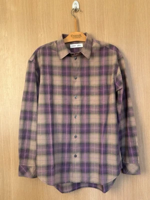 Samsøe Saluan J Shirt - Säljer en helt ny rutig skjorta från Samsøe Samsøe i beige och lila toner. Skjortan har klassisk krage, långa ärmar och knäppning framtill. Perfekt för dig som gillar en avslappnad men ändå stilren look.