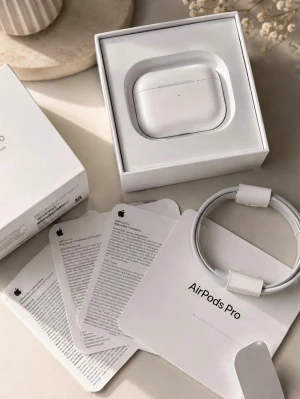 Apple AirPods Pro trådlösa hörlurar - Säljer ett par vita Apple AirPods Pro med laddningsetui och USB-C kabel. Hörlurarna har en stilren och kompakt design i blank plast och levereras i originalförpackning med manualer. Perfekta för musik, samtal och träning.
