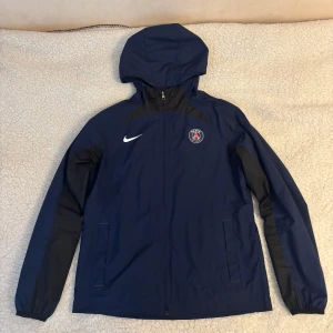 PSG x Nike blå vindjacka med huva - Säljer en mörkblå Nike PSG jacka i storlek M som är i mycket bra skick. 