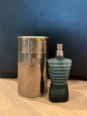 Jean Paul Gaultier Le Male parfym - Klassisk parfymflaska formad som en manlig torso i mörkgrönt glas med ljusare ränder. Kommer med en metallisk, cylinderformad förpackning med präglad logga. En ikonisk doft som sticker ut i badrumshyllan. 75ml flaska men är ungefär 45 ml kvar🙌🏼