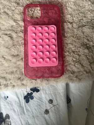 iPhone 13 Rosa mobilskal med pop it-detalj - Säljer ett genomskinligt rosa mobilskal med en inbyggd pop it-leksak i ljusrosa på baksidan. Skalets material är mjuk plast och pop it-delen är i silikon. Perfekt för dig som gillar att pilla på något när du har tråkigt. Och kan sätta fast mobilen    Pris diskuteras.