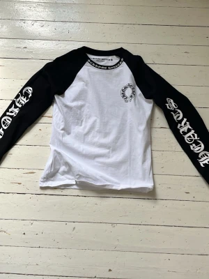 Svartvit långärmad T-shirt Chrome Hearts - Säljer en svartvit långärmad T-shirt från Chrome Hearts med kontrastärmar och tryck på både ärmar, bröst och rygg. Oversized streetwear-vibe med cool grafik och logga. Perfekt för dig som gillar statement-plagg och vill sticka ut. Hör gärna av er om ni har några övriga frågor😃