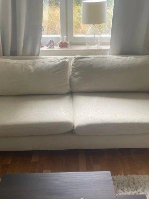 Beige soffa med mjuka dynor - Säljer en stilren beige soffa med två stora sittdynor. Soffan har en enkel och modern design med raka linjer och tygklädsel. Perfekt för vardagsrummet och passar till många olika inredningsstilar. Köpt för 14000kr säljer för 6000kr, pris kan diskuteras.