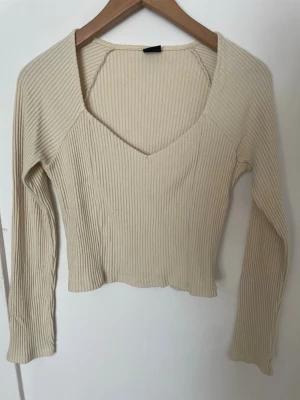 Ribbad croppad topp - Säljer en ljusgul ribbad topp med v-ringning och långa ärmar. Toppen är croppad och har en mjuk, stretchig passform som sitter snyggt på kroppen💛