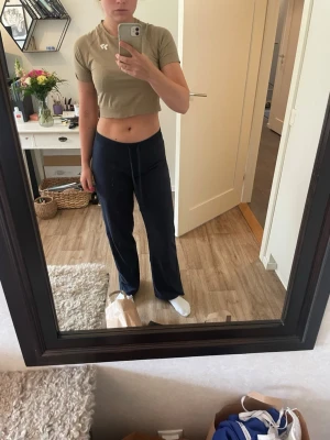Beige cropped träningstopp - Snygg beige cropped träningstopp med korta ärmar och rund hals. Tillverkad i ett stretchigt och mjukt material som andas, perfekt för gymmet eller annan träning. Diskret logga på bröstet för en sportig look. (Crop top passar även S)