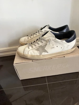 Golden goose - Säljer ett par vita Golden Goose sneakers med grå stjärna på sidan och svart hälparti. Köpta förra sommaren på Paris outlet store. Papers Kvitto finns, fråga gärna. Strl 44 men passar 43