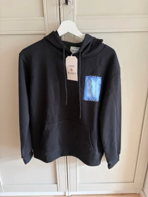 Svart hoodie med blå detalj Casa Blanca - Storlek xs. Jag som har S i storlek får på mig den men tröja är kort på mig