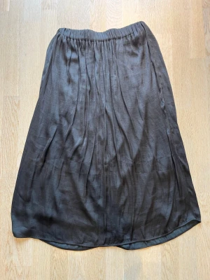 Svart långkjol med resårmidja - Säljer en enkel och stilren svart långkjol med resår i midjan. Kjolen har ett tunt, lätt material med ett slätt innerfoder som ger extra komfort. Passar perfekt till olika outfits och har en mjuk, flytande siluett. Tveka inte på att skriva en fråga eller be om fler bilder.🌸🌸