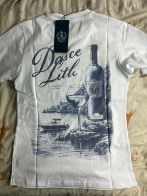 Vit t-shirt från Leon Marcel - Snygg vit t-shirt från Leon Marcel med diskret tryck 'Marcel' i marinblått på bröstet. Klassisk rund halsringning och korta ärmar. Tillverkad i mjuk bomull som känns skön mot huden. Perfekt basplagg för en clean och stilren look.