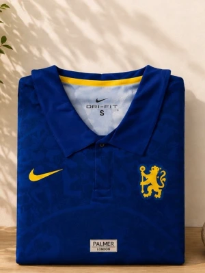 chelsea Blå fotbollströja med krage - Har också en L om du vill ha. Snygg blå fotbollströja från Nike med krage och gula detaljer. Tröjan har ett gult lejonmärke på bröstet, gul Nike-logga och diskreta mönster i tyget. Tillverkad i Dri-FIT material som andas, perfekt för träning eller match.
