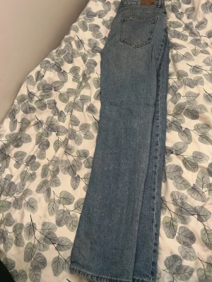 Blå raka jeans  - Säljer ett par blå jeans med rak passform och hög midja. Jeansen har fem fickor och är gjorda i ett klassiskt denimtyg. Perfekta för en avslappnad och tidlös stil.