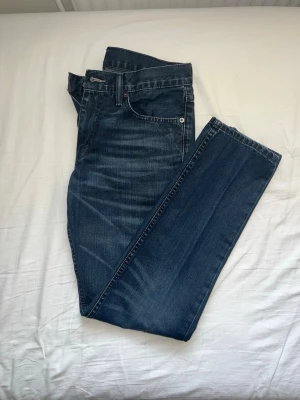 Levi’s jeans - Säljer ett par mörkblå jeans med raka ben och klassisk femficksmodell. Jeansen har subtila slitningar och kontrastsömmar för en snygg look. Tillverkade i denim med en skön passform som funkar till det mesta. Finns att hämta i Södertälje 