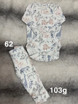 Body och byxa med djurmönster, stl 62 - Supersött set med långärmad body och matchande byxa i vitt med djurmotiv i blått och beige. Tryckknappar i grenen på bodyn för enkel påklädning. Perfekt för små äventyrare som gillar mjuka och bekväma kläder.🌸 Fint använt skick. Storlek 62