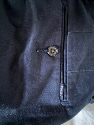 Marinblå chinos från Polo Ralph Lauren - Snygga marinblå chinos från Polo Ralph Lauren med klassisk passform. Byxorna har bakficka med knapp och diskret Polo-märke vid fickan. Tillverkade i ett mjukt och slitstarkt bomullstyg, perfekta för en clean och stilren look.