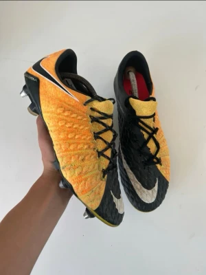 Nike Hypervenom svart/gul fotbollsskor - Säljer ett par Nike Hypervenom fotbollsskor i svart och gul med vit swoosh. Skorna har strukturmönstrad ovandel för bättre bollkontroll och fasta dobbar för spel på gräs. Snygg design med svart snörning och låg profil.