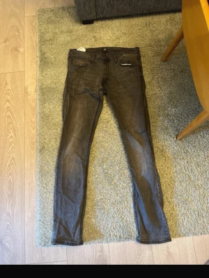 Grå slim fit jeans från Lee - Snygga grå slim fit jeans från Lee med klassisk femficksdesign och dragkedjegylf. Jeansen har en smal passform och är tillverkade i ett mjukt denimtyg som sitter skönt. Perfekta för en avslappnad och trendig look.