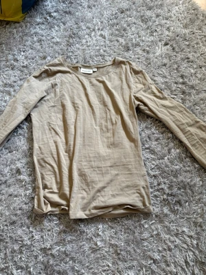 Beige långärmad topp från Kappahl - En enkel och stilren beige långärmad topp från Kappahl i mjuk bomull. Perfekt basplagg med rund halsringning och normal passform. Lätt att matcha till olika outfits och superbekväm att bära.